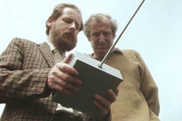 Two men holding a remote control device