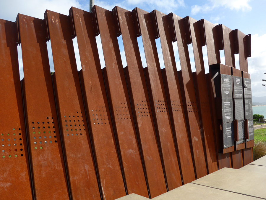 Line of connected bronze panels with black plaque with text at the end of the row