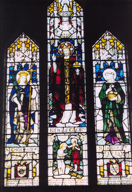View of brightly coloured stained glass window with religious figures on three panels