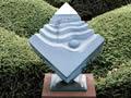 Stone memorial in diamond shape with wavy lines mounted on a plinth
