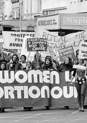 Women marching on street with various signs including pro-abortion messages
