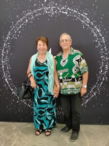Man and Woman in Pacific island clothes standing in front of white circle painted n black wall