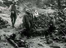 Army medics near a hole surrounded by debris. A solider lies on a stretcher nearby