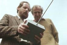 Two men holding a remote control device