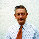 Elderly man in white printed shirt and red tie