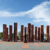 A group of red coloured pillars arranged on a concrete foundation