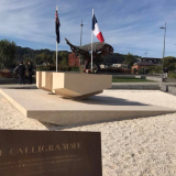 Stone blocks sitting on limestone gravel with New Zealand and French flags in the background