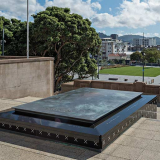 Bronze and marble tomb set into concrete steps with park in the background
