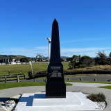 Black granite obelisk set into concrete inlaid with the words Lest we Forget