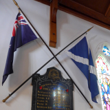Wooden board hanging on wall between two crossed flags