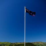 Flagpole next to picnic table with sea and boats in the background