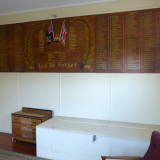 Wooden plaque fixed on a wall with lists of names in gold lettering