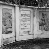 Marble stone memorial consisting of a central panel of text flanked by reliefs of human figures.