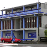 Blue and grey concrete building with red car parked outside.