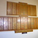 Wooden plaques fixed on a wall with lists of names in gold lettering