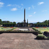 Landscaped grass and gardens with concrete mausoleum and obelisk in the background