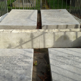 Four rectangular stone tablets with writing on them behind an iron fence