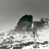 Man standing in snow blizzard surrounded by plan wreckage