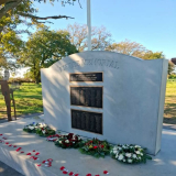 Memorial wall with plaques listing names and a flagpole