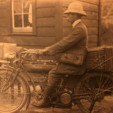Cromwell Shepherd sitting on a motorbike outside of a house.