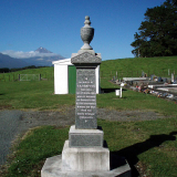 Stone obelisk with buildings, trees and mountain in the background