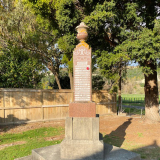 Stone column with names inscribed on each side sitting atop a concrete plinth