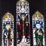 View of brightly coloured stained glass window with religious figures on three panels