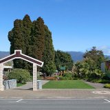 Grass park with Māori waharoa (gateway) in the foreground and mountains in the background