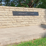 Granite cenotaph set into concrete base on green grass.