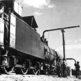 Men in uniform standing on and beside train engine and carriages.