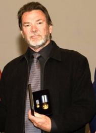 Man standing and holding two medals