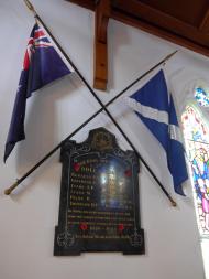 Wooden board hanging on wall between two crossed flags