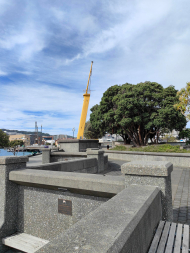 Yellow ships mast surrounded by concrete walls and large pohutukawa tree