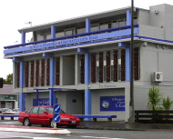 Blue and grey concrete building with red car parked outside.