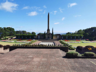 Landscaped grass and gardens with concrete mausoleum and obelisk in the background
