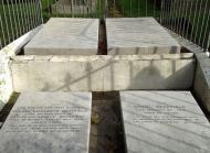Four rectangular stone tablets with writing on them behind an iron fence