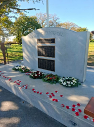 Memorial wall with plaques listing names and a flagpole