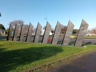 Sculpture of nine slanted columns representing soldiers and their horses marching
