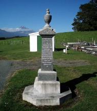 Stone obelisk with buildings, trees and mountain in the background