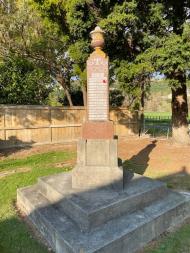 Stone column with names inscribed on each side sitting atop a concrete plinth