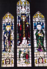 View of brightly coloured stained glass window with religious figures on three panels