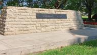 Granite cenotaph set into concrete base on green grass.