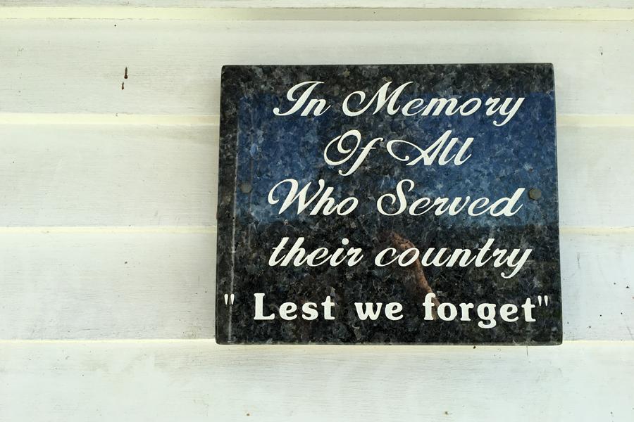 Black marble plaque with text inscription attached to white weatherboard