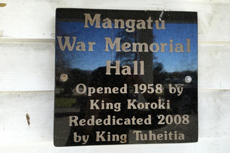 Black marble plaque with inscription attached to white weatherboard wall
