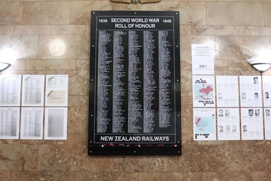 Black plaque with list of names attached to marble wall