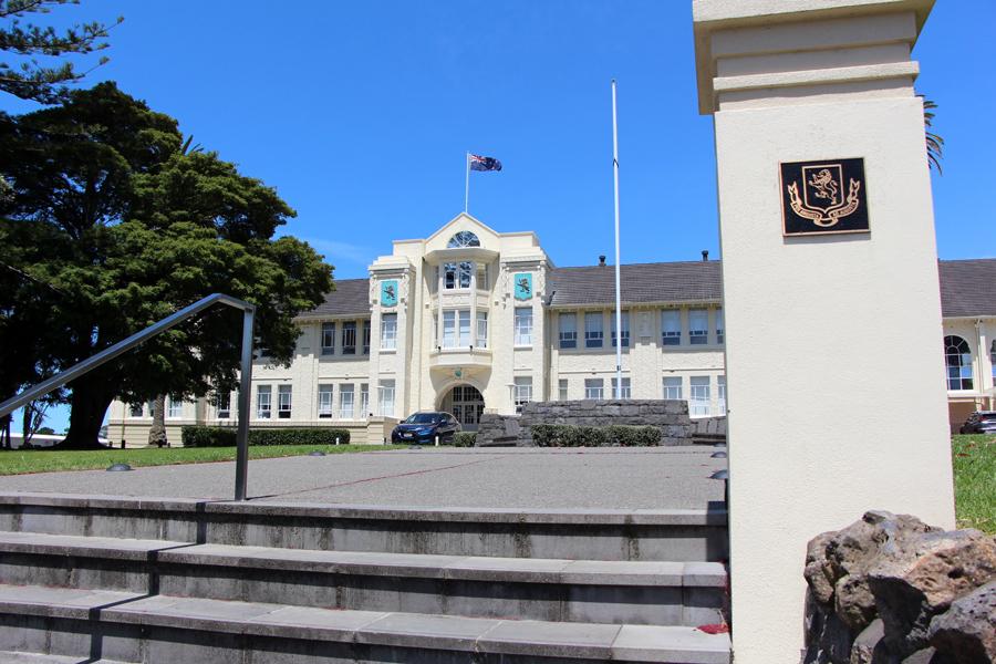 View of front entrance of art deco building with the New Zealand flag flying from the roof