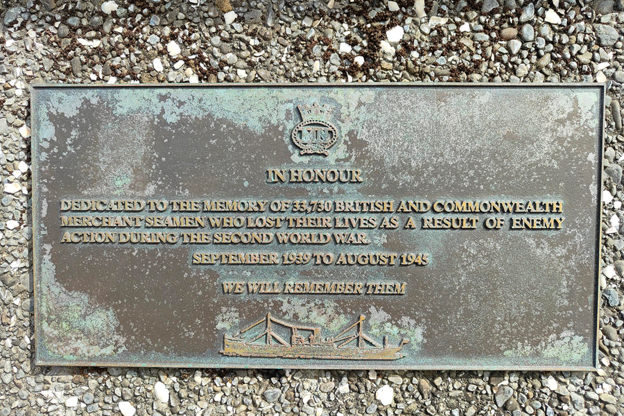 Commemorative plaque with Merchant Navy badge and profile of ship attached to wall