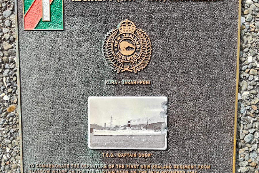 Commemorative plaque with green and red 1 insignia and New Zealand Regiment badge attached to wall