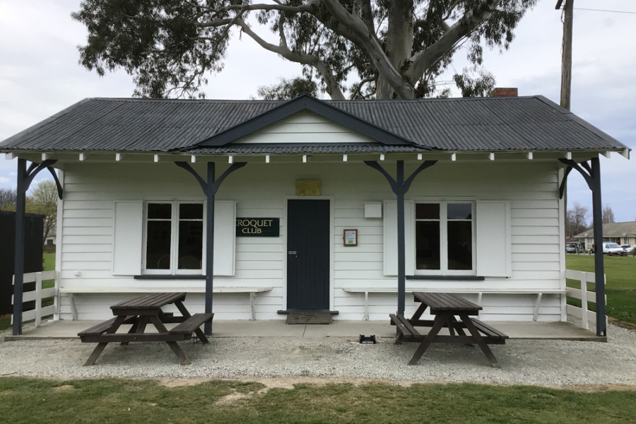 Exterior view of white wooden building with two picnic tables outside front door