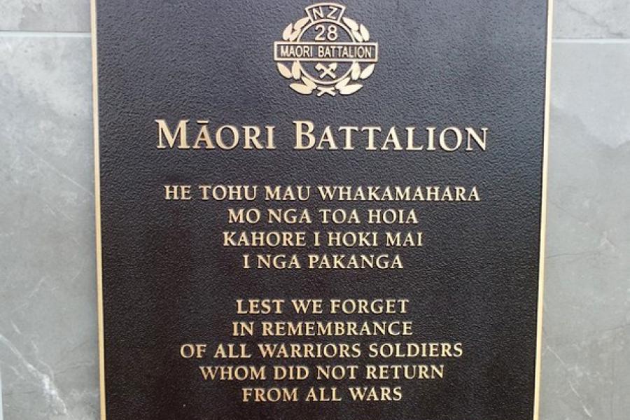 Square bronze plaque with gold text in te reo Māori and English under emblem of 28 Māori Battalion and heading Māori Battalion